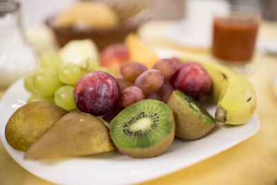 Bunter Frühstücksteller mit Kiwi, Banane, Traube, Birne und Pflaume